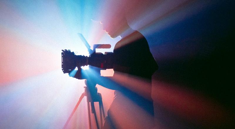 Camera operator filming against stage lights
